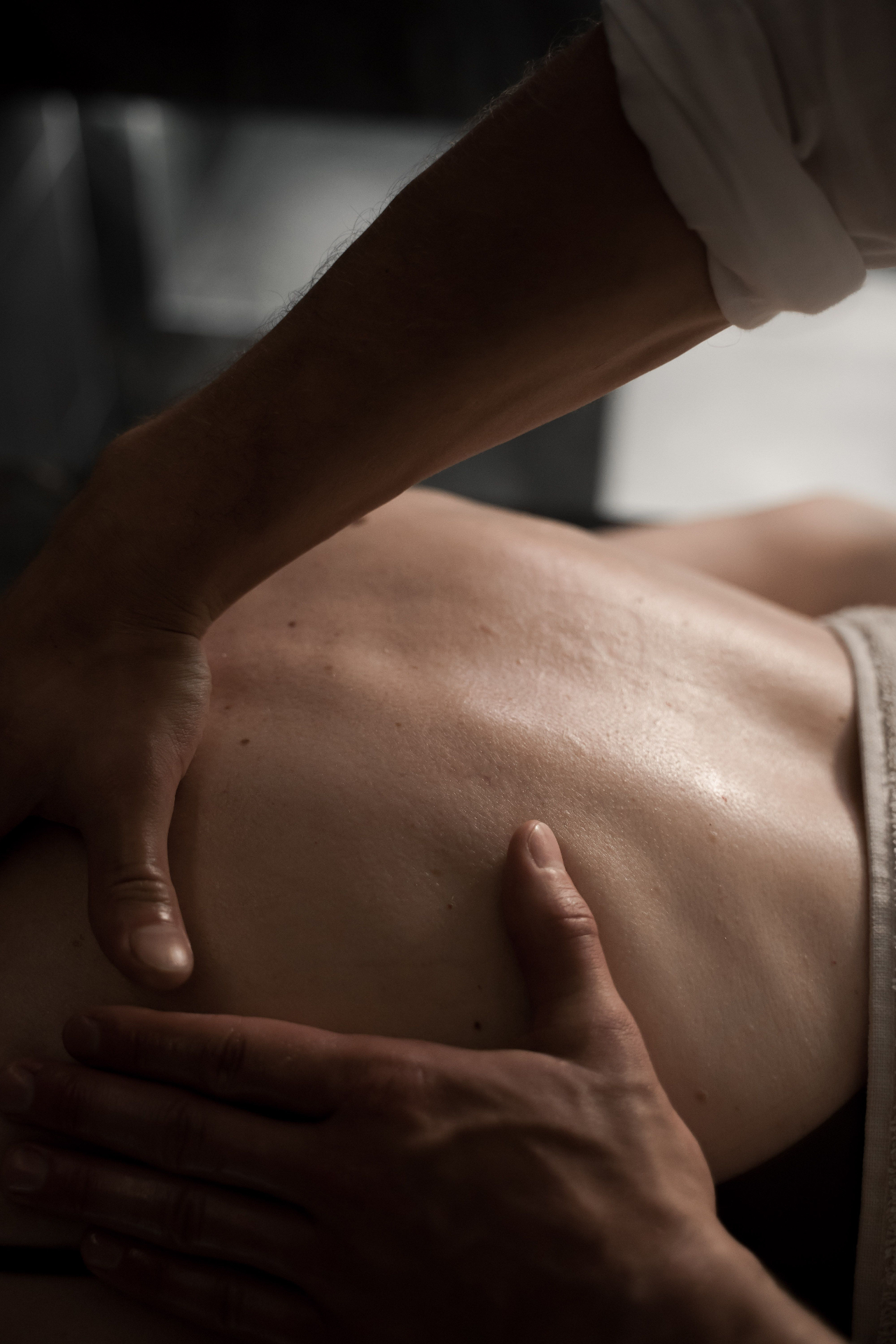A therapist giving a back massage in a calm, plant-filled treatment room